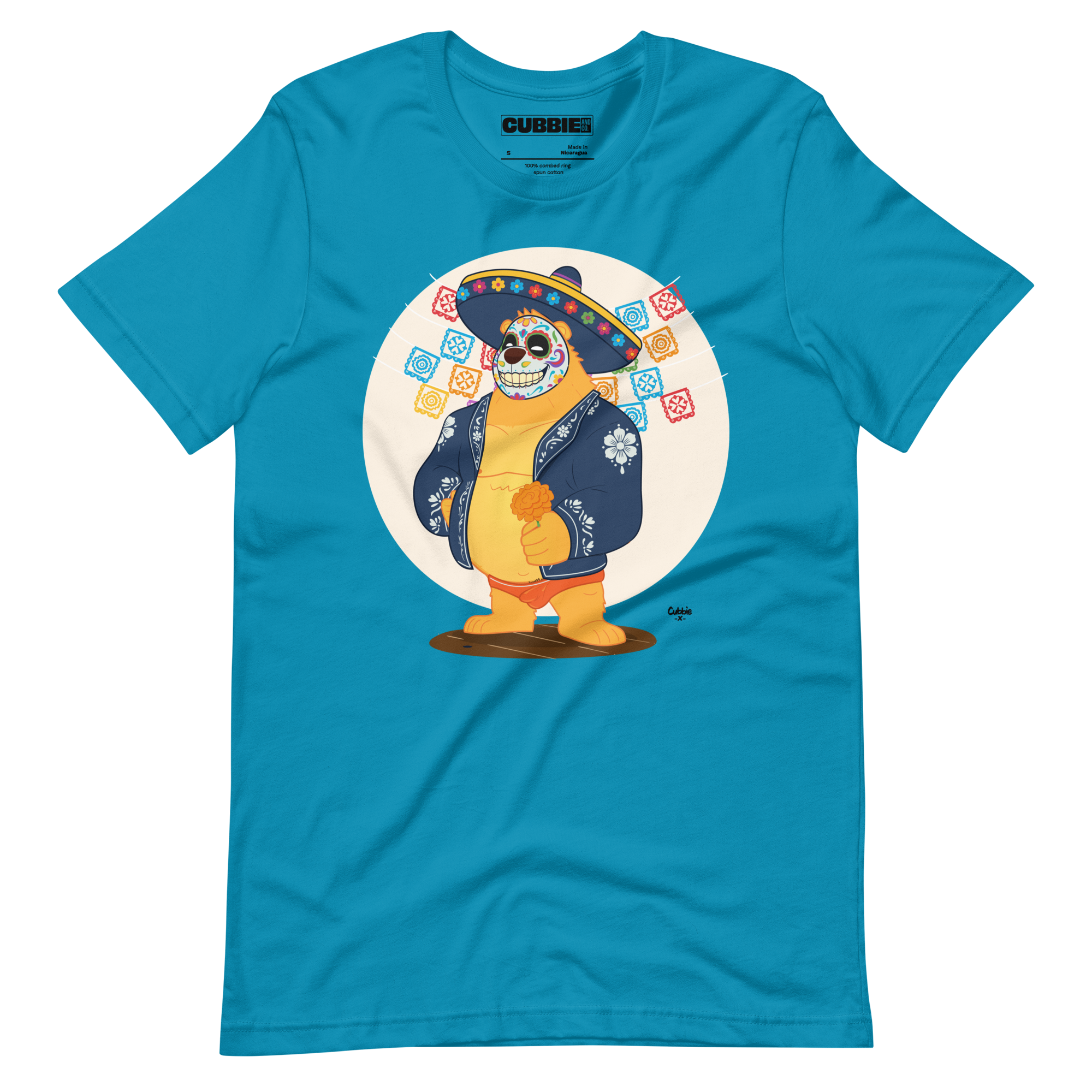 Bright aqua blue t-shirt featuring a cartoon LGBTQ+ bear character celebrating Day of the Dead, wearing a sombrero and traditional Mexican clothing