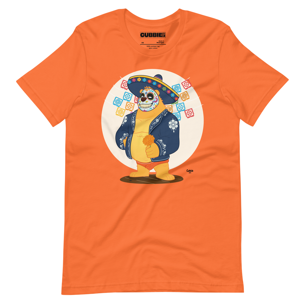 Orange t-shirt featuring a cartoon LGBTQ+ bear character celebrating Day of the Dead, wearing a sombrero and traditional Mexican clothing