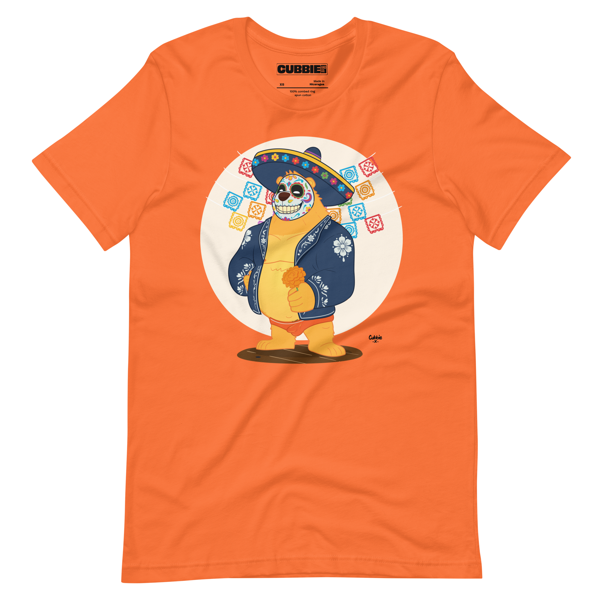 Orange t-shirt featuring a cartoon LGBTQ+ bear character celebrating Day of the Dead, wearing a sombrero and traditional Mexican clothing
