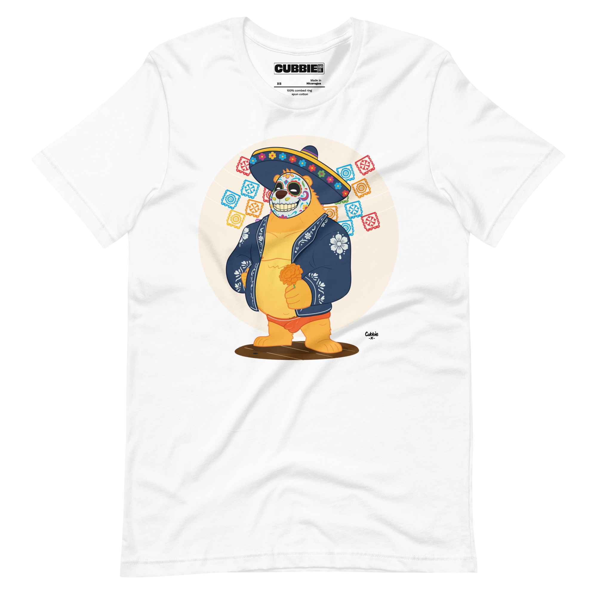 White t-shirt featuring a cartoon LGBTQ+ bear character celebrating Day of the Dead, wearing a sombrero and traditional Mexican clothing